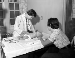 Doctor examining baby, 1961