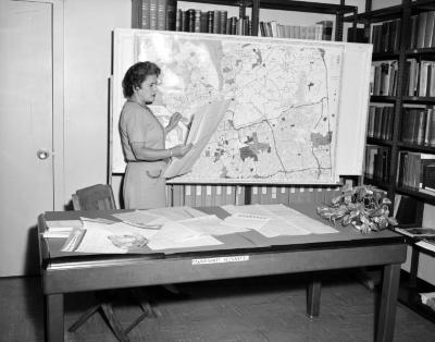 Community resources worker looking at a map of Hempstead, 1961