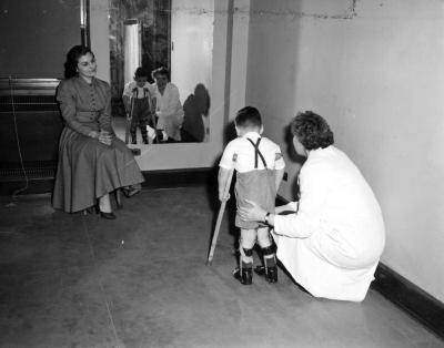 Nurse assisting a handicapped child on crutches