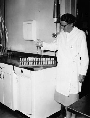 Scientist using syringe to fill vials