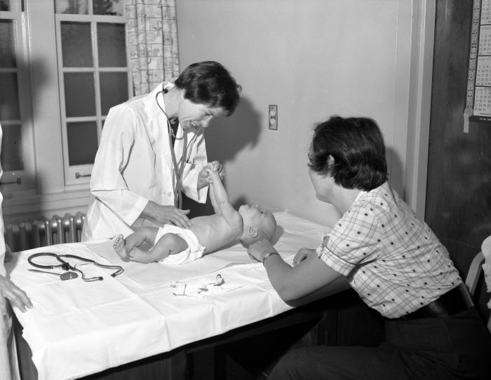 Doctor examining baby, 1961