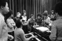 Members of the Afro-American Total Theatre gathered around a piano