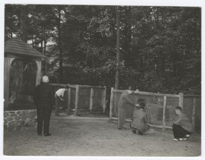 People looking at animals in cages at a zoo at Belmont Lake State Park