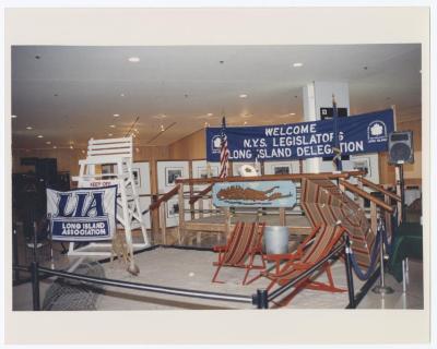 Indoor beach scene set and banner reading: Welcome NYS Legislators Long Island Delegation