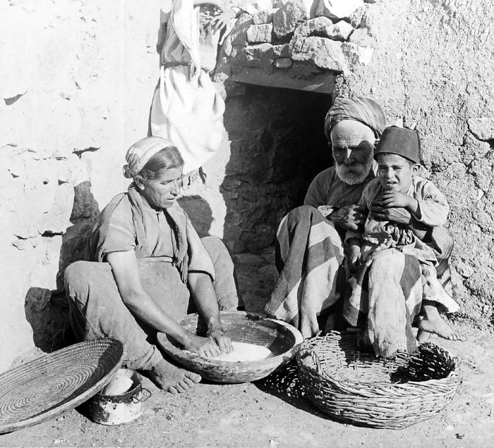 Syria.  Woman Kneading Bread outside the Door of an Oven; Man and Small Boy