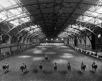 Interior of riding hall, cadets on horseback