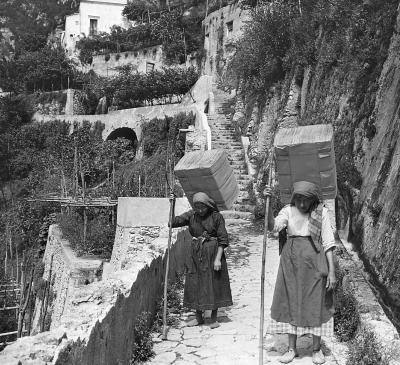 Italy.  Amalfi.  Women Carrying Large Bales of Paper