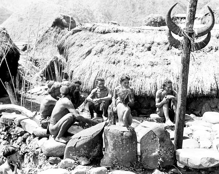 Philippine Islands.  Luzon.  Bontoc Igorots Seated before Thatched Hut