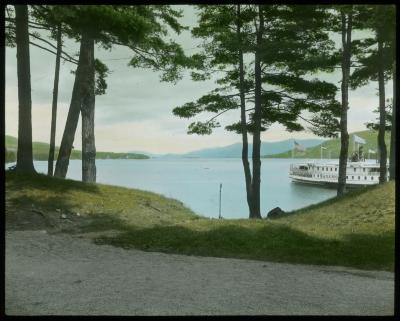 View down the Lake [George] from Fort William Henry Grounds: Steamer Sagamore at Dock, Pine Trees