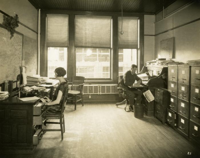 Official and assistant in a sunlit office, 1924