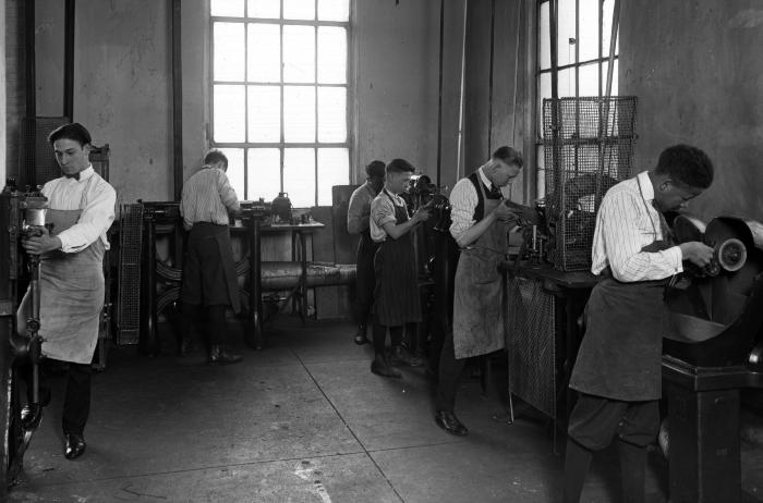 Young men working at machinery in trade school classroom