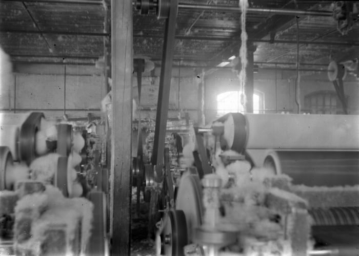 Men's underwear factory:  carding room with machinery, narrow aisles