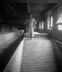 Glass factory:  man tamping clay with bare feet at a glass factory in Corning, New York (different views).