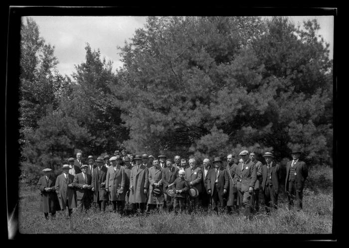 Group of men pose at the edge of a pine forest