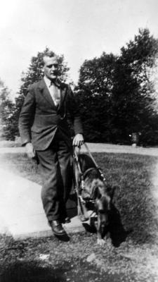 Unidentifed photo of man walking seeing eye dog.