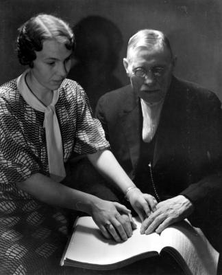 Woman teaching man braille.