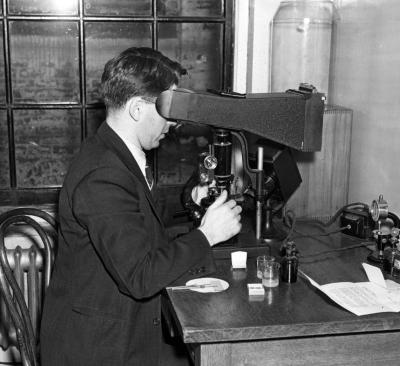 Paper Mill Laboratory. Chemist examining paper for texture and porosity. Springfield, Massachusetts