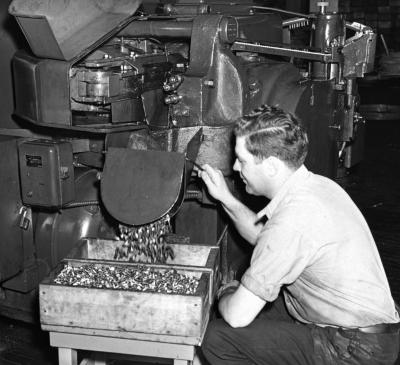 Manufacture of bolts. Finished bolts falling into box from cutting and stamping machine. Hartford, Connecticut