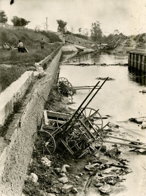 Agricultural implements thrown into the canal by the Germans, with a destroyed bridge in the background, in Tugny et Pont (Aisne), France