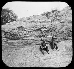 Section of clay bank and laborers at brickmaking facility.