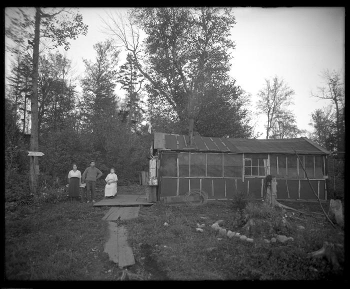 Two women and a man standing outside home