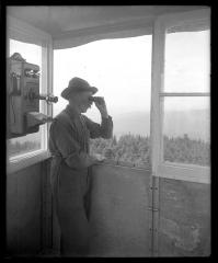 An observer with field glasses in the CC's forest fire observation station on the lookout for smoke