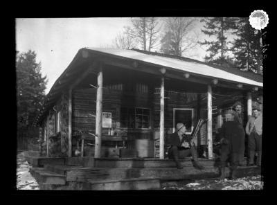 Men on the porch of a log cabin