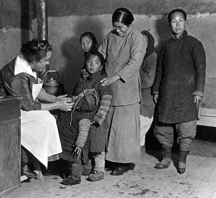 Doctor examining a child; nurses, mother and children, China