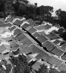 Village street flanked by tile roof houses separated by courtyards, Szechwan Province, China